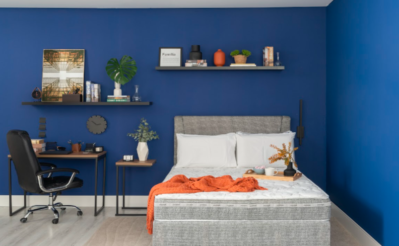 tamanho de colchão de casal em um quarto com cama, travesseiros, escrivaninha, prateleira e cadeira de escritório.