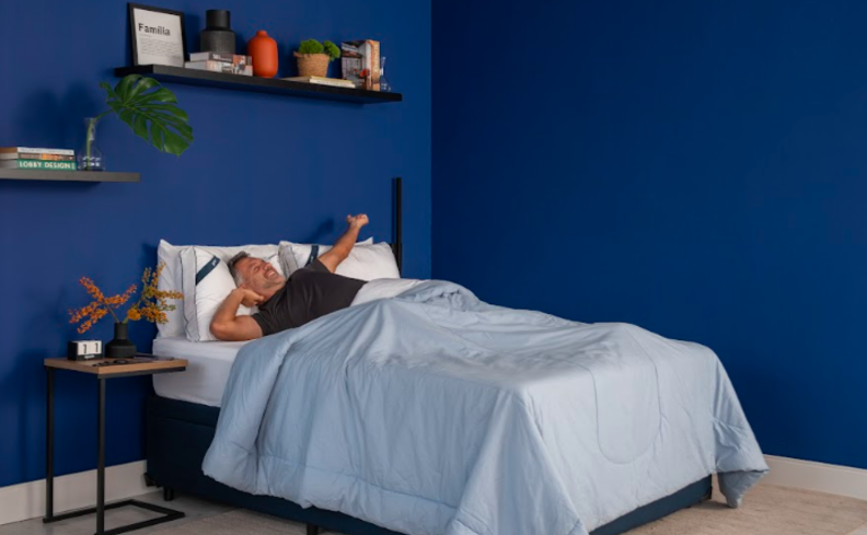 homem deitado em uma cama no quarto com travesseiros, edredom e diversos itens de decoração querendo saber o que causa insônia