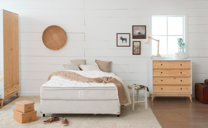 como limpar colchão encardido em um quarto com cama e colchão de casal, tapete, cômoda de madeira, mesa de apoio e diversos itens decorativos.