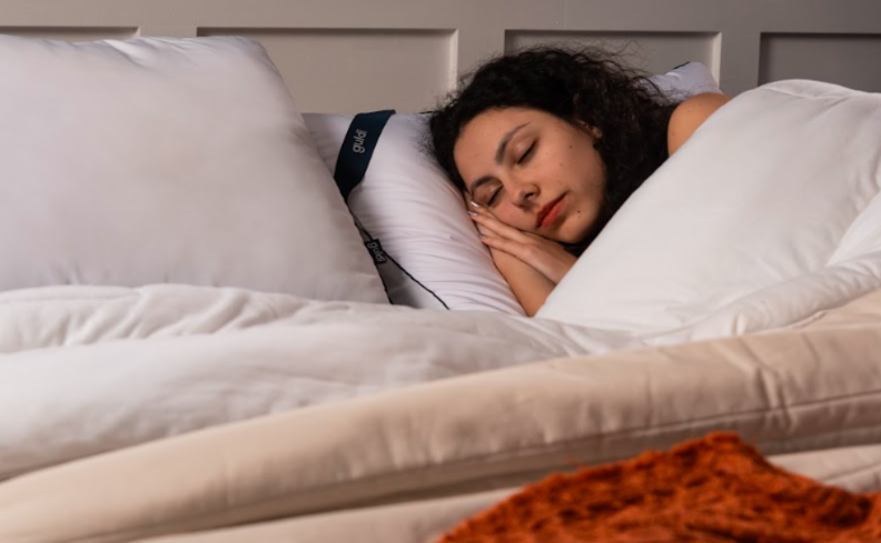 como ter um sono saudável, uma pessoa deitada na cama dormindo com travesseiros e cobertores