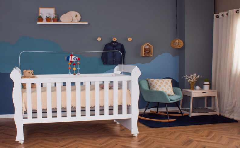 quarto de criança com berço, colchão infantil para berço, poltrona, mesa lateral, prateleira e itens decorativos