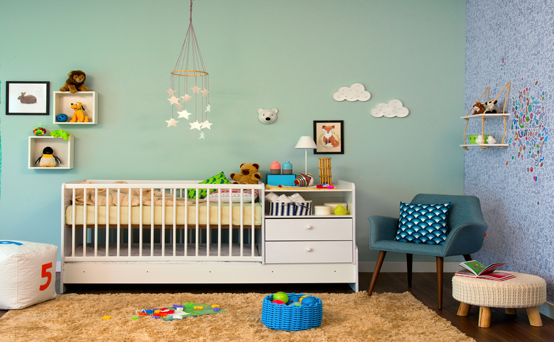 quarto de criança com colchão infantil, berço, poltrona com almofada, puffes, tapete e outros itens de criança