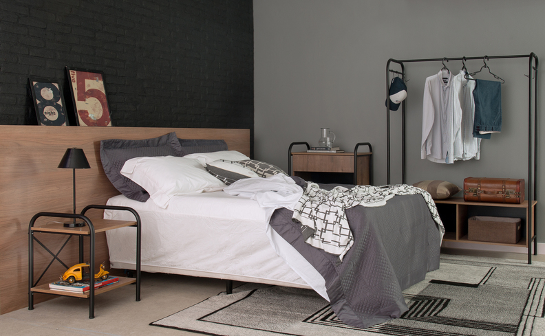 quarto com cama, travesseiro regulável, tapete, mesa de cabeceira, arara de roupas e acessórios de decoração