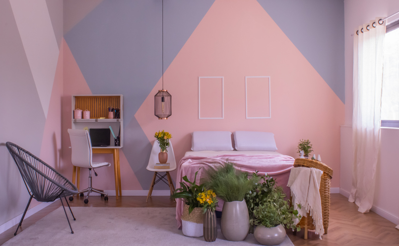 quarto simples de casal com poltrona, cama, colchão, escrivaninha, cadeira de escritório, pendente e diversos itens de decoração