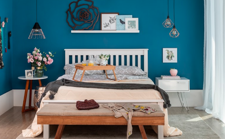 base de cama baú em um quarto de casal com mesa de cabeceira, prateleiras e pendentes