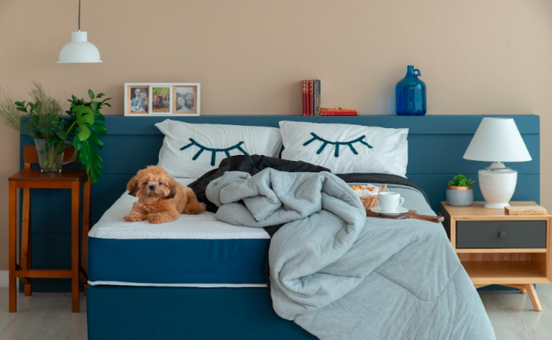 quarto com um colchão que vem enrolado, roupa de cama, travesseiros, mesas de cabeira para ter um ambiente confortável e aproveitar o dia do sono
