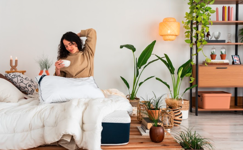 noite mal dormida com uma pessoa sentada na cama em um quarto com estante, itens decorativos e roupas de cama