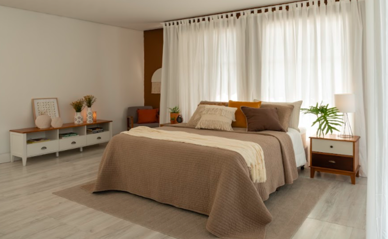 colchão casal macio e confortável em um quarto com cama posta, tapete, aparador, mesa de cabeceira e itens decorativos.