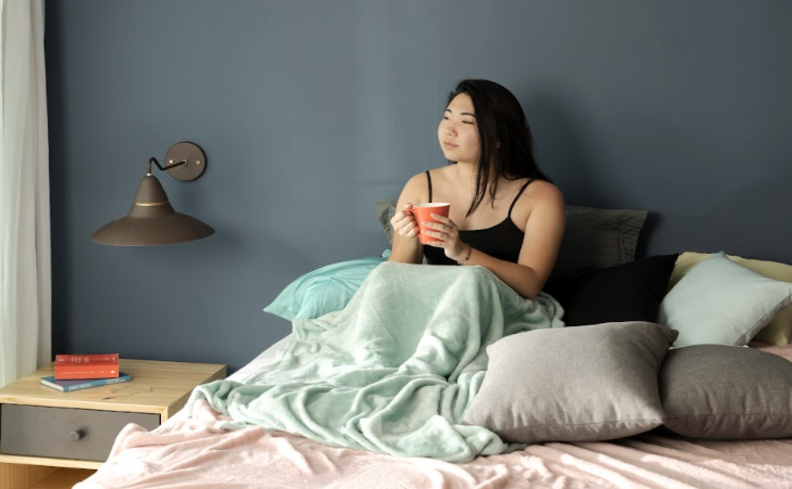 mulher sentada na cama pensando o que pode causar insônia e o que são os distúrbios do sono.