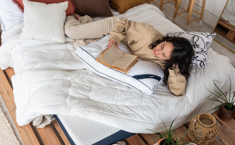 mulher deitada em um colchão lendo sobre o que é paralisia do sono para ter noites de sono mais confortáveis