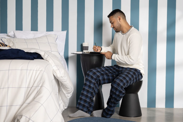 homem sentado em um banco no quarto vendo que ler antes de dormir faz bem e ajuda a melhorar a qualidade do sono.