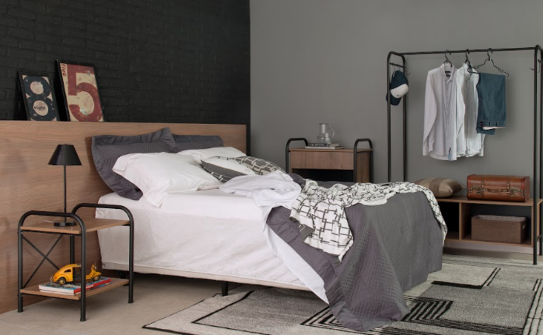 qualidade do sono em um quarto completo com cama, colchão, roupas de cama brancas e cinzas, tapete, arara de roupas, mesa de cabeceira e diversos itens decorativos.