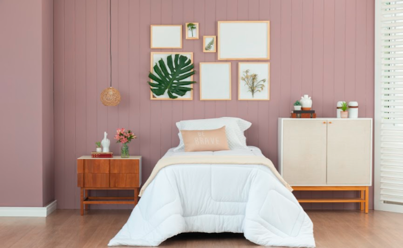 quarto de visita pequeno com cama, mesa de cabeceira, cômoda e diversos itens decorativos como lustre pendente, quadros e vasos de plantas.