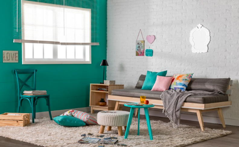 quarto de visitas na sala de estar, com um sofá cama confortável, além de cadeira, puffs, mesa de apoio e diversos itens decorativos.