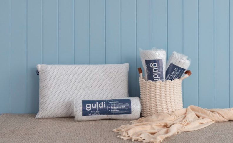 como lavar travesseiro sem danificar e sem deixar com fungos e ácaros, com três travesseiro da guldi enrolados e um aberto, além de uma manta e um cesto.