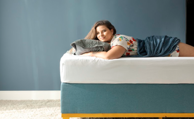 mulher deitada de bruços em uma cama com travesseiro e cobertor pensando se cochilar depois do almoço é bom ou ruim para a qualidade do sono ao longo do dia.