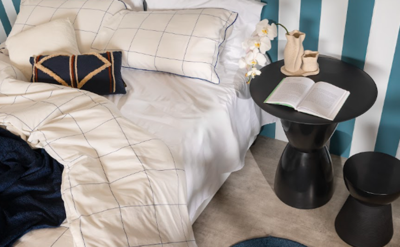 é normal ter insônia na gravidez? quarto com cama, roupa de cama branca e azul, mesa de cabeceira preta e banco.