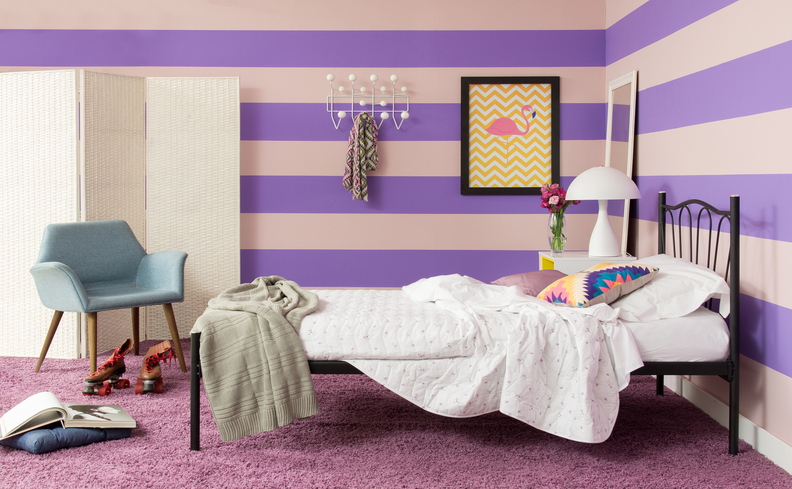 descubra de quanto em quanto tempo tem que trocar o colchão em um quarto com parede colorida, cama com colchão, edredom branco, poltrona e diversos itens decorativos.