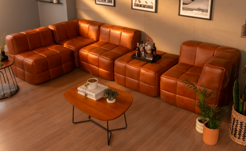 sofá modular couro, em corino na cor marrom, na sala de estar com mesa de centro vasos com plantas e uma bandeja em um dos módulos.