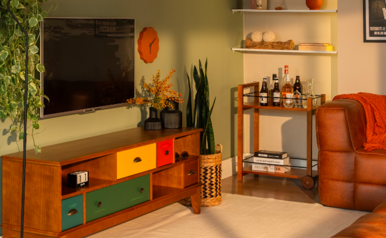 poltronas para sala de TV pequena com painel com TV suspensa, carrinho bar, vaso com plantas, relógio de parede, sofá modular, estantes, tapete e diversos itens decorativos.