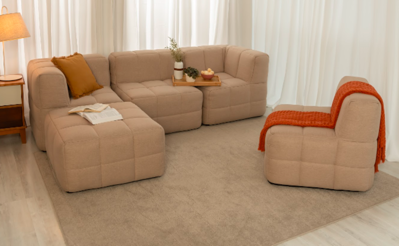 sofá para sala pequena em módulos na cor bege, tapete, mesa lateral e manta para sofá laranja.