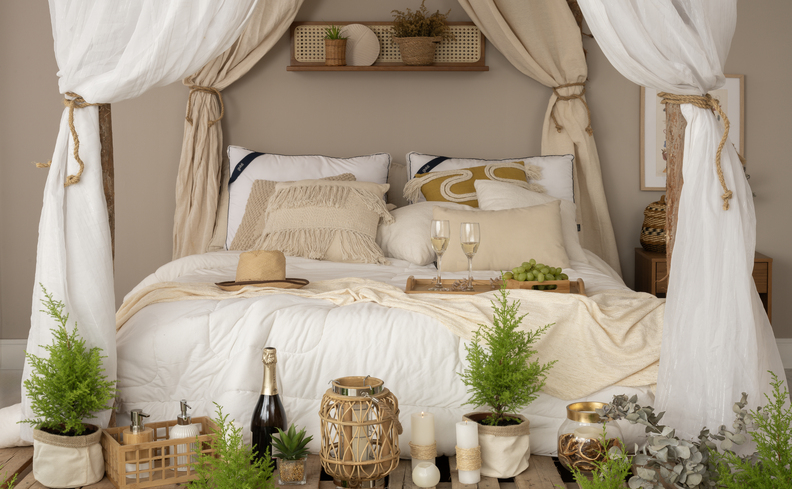 colchão com pillow top, diversas almofadas e travesseiros para saber como fazer a cama igual a de hotel em casa, além de diversas plantas e um mosqueteiro.